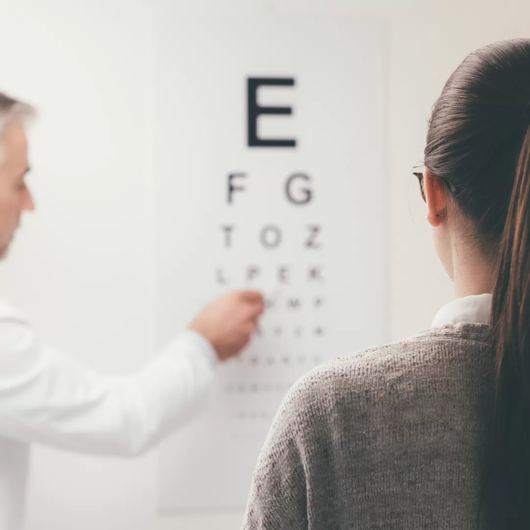 Pessoa a realizar um teste de acuidade visual com tabela optométrica