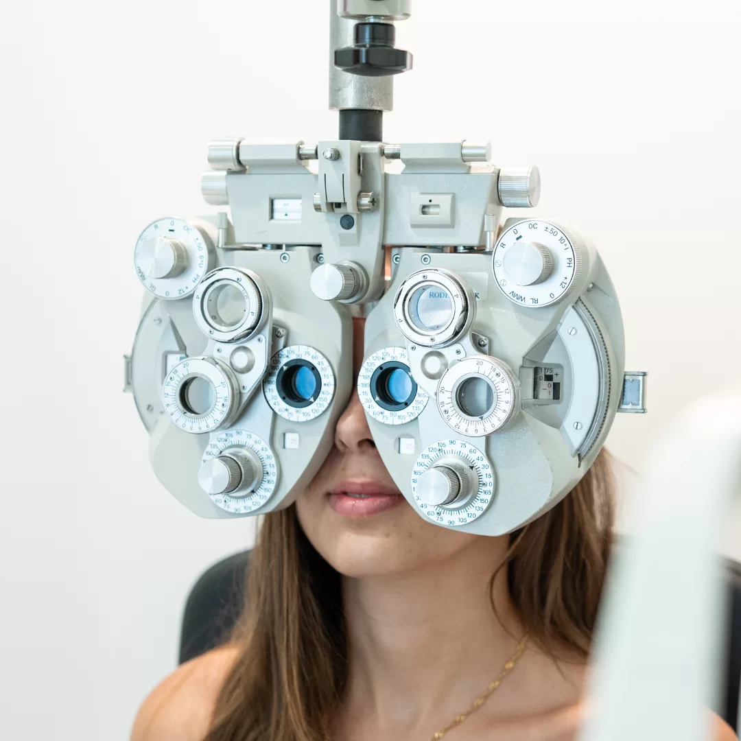 Pessoa durante avaliação da graduação com foróptero numa consulta de optometria